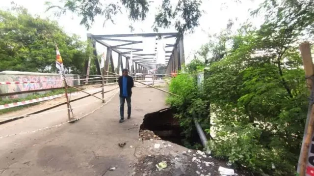 Lubang akibat longsor di jalan pendekat jembatan Cipamingkis Cibarusah kian meluas. Kondisi ini membuat sejumlah pengendara harus melintas secara bergantian akibat separuh badan jalan telah tergerus aliran sungai.