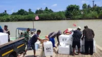 Proses pemindahan kotak suara ke atas perahu di dermaga kantor Kecamatan Muaragembong untuk dibawa ke Desa Pantai Bahagia, Minggu (11/02) siang.