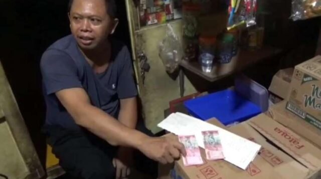 Udin Kopral (45) seorang pedagang kopi di Desa Setiadarma, Kecamatan Tambun Selatan, Kabupaten Bekasi saat menunjukan perbedaan uang asli dan uang palsu yang diterimanya dari pembeli, Sabtu (23/03) malam.
