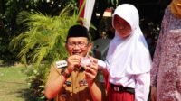 Pj Bupati Bekasi Dani Ramdan saat memberikan kartu identitas anak (KIA) kepada salah seorang anak pada acara Botram tingkat Desa di Perum Graha Cikarang, Desa Simpangan Kecamatan Cikarang Utara, Kabupaten Bekasi.