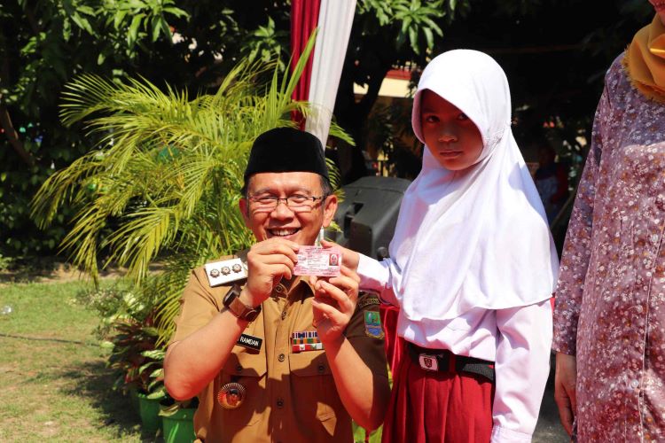 Pj Bupati Bekasi Dani Ramdan saat memberikan kartu identitas anak (KIA) kepada salah seorang anak pada acara Botram tingkat Desa di Perum Graha Cikarang, Desa Simpangan Kecamatan Cikarang Utara, Kabupaten Bekasi.