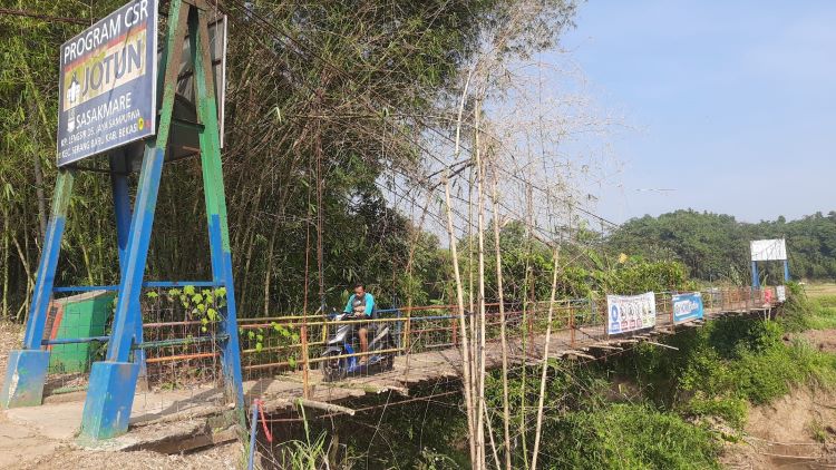 Salah seorang pengendara melintasi jembatan gantung Sasakmare yang menghubungkan Desa Jayasampurna, Serang Baru dengan Desa Kertarahayu, Setu