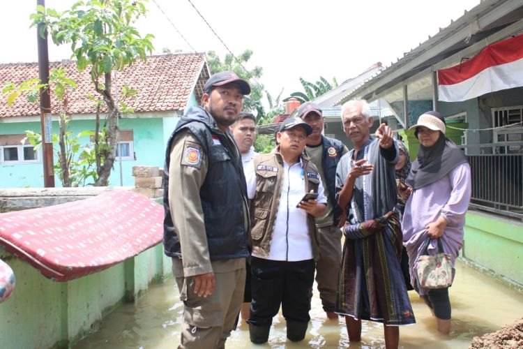 Camat Sukatani Agus Dahlan meninjau lokasi banjir di wilayahnya. Banjir tersebut diakibatkan luapan dari Kali Cikarang yang tidak dapat menampung debit air dari tingginya curah hujan beberapa hari lalu.