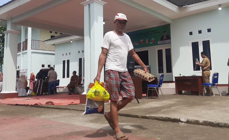 Salah seorang warga saat membawa pulang paket sembako murah dalam acara Gerakan Pangan Murah (GPM) di di Desa Sukasejati, Kecamatan Cikarang Selatan, Kabupaten Bekasi, Senin (02/12).