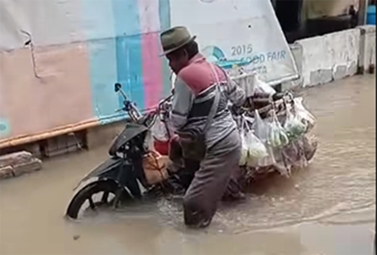 Seorang pedagang sayur keliling menerjang banjir rob di Desa Pantai Bahagia, Kecamatan Muaragembong, Minggu (16/12) kemarin.