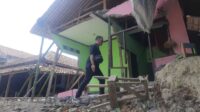 Salah seorang warga melintasi salah satu rumah yang nyaris roboh akibat longsor di di Kampung Tembong Gunung, Desa Sukamahi, Kecamatan Cikarang Pusat, Kabupaten Bekasi.