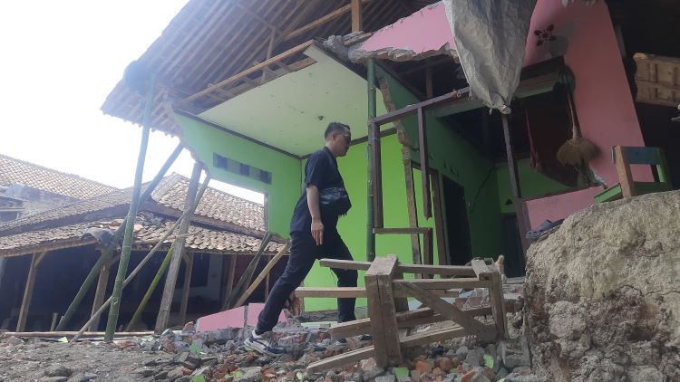 Salah seorang warga melintasi salah satu rumah yang nyaris roboh akibat longsor di di Kampung Tembong Gunung, Desa Sukamahi, Kecamatan Cikarang Pusat, Kabupaten Bekasi.
