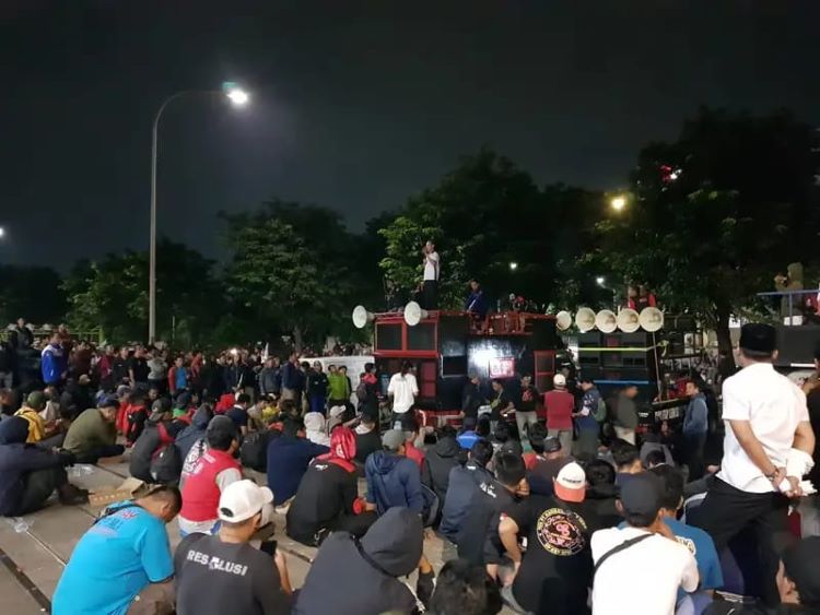 Aksi unjuk rasa yang dilakukan oleh Federasi Serikat Pekerja Metal Indonesia (FSPMI) dan Aliansi Buruh Bekasi Melawan (BBM) kembali berlangsung di depan PT Yamaha Music Manufacturing Asia (YMMA) di kawasan industri MM2100, Cikarang Barat, Kabupaten Bekasi, pada Kamis (03/07). Hingga pukul 21.30 WIB, massa aksi masih bertahan di depan gerbang perusahaan untuk menyuarakan tuntutannya.