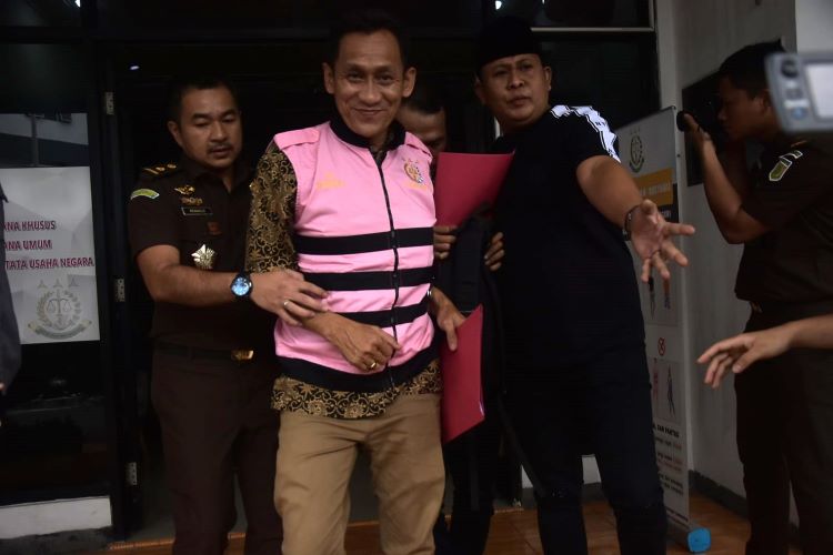 Mantan Sekdes Sumberjaya, SJ terlihat sumringah saat mengenakan rompi tahanan berwarna merah muda dan hendak dibawa ke Lembaga Pemasyarakatan Kelas IIA Cikarang. Ia bahkan tampak tersenyum lebar di hadapan kamera.