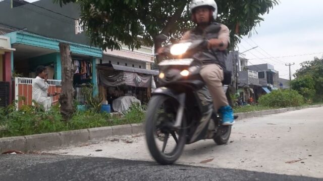Seorang pengendara motor melintasi jalan lingkungan di Perumahan BCM, Desa Sukadami, Kecamatan Cikarang Selatan, Kabupaten Bekasi yang telah rampung dibangun, Jum'at (12/12).