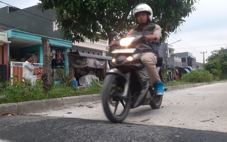 Seorang pengendara motor melintasi jalan lingkungan di Perumahan BCM, Desa Sukadami, Kecamatan Cikarang Selatan, Kabupaten Bekasi yang telah rampung dibangun, Jum'at (12/12).
