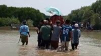 Potret perjuangan warga Kp Beting, Desa Pantai Bahagia, Kecamatan Muaragembong, Kabupaten Bekasi saat menerjang air setinggi lutut hingga paha akibat banjir rob demi memakamkan salah seorang warga yang meninggal dunia.