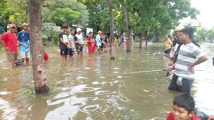 Warga Perumahan Puri Nirwana Residence di Desa Sukaraya, Kecamatan Karang Bahagia, Kabupaten Bekasi tampak asyik memancing ikan lele yang sengaja ditebar untuk menghibur masyarakat yang terdampak banjir di kawasan tersebut, Senin (19/01).