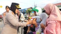 Kapolres Metro Bekasi, Kombes Sumarni saat membagikan biskuit dan susu kepada pengendara roda dua yang melintas di depan Pos Terpadu Gedung Juang 45 Tambun Selatan, Kabupaten Bekasi, Senin (23/03).
