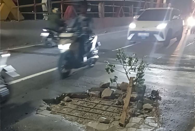 Kondisi lubang di Flyover Tegal Gede Desa Pasirsari, Kecamatan Cikarang Selatan, Kabupaten Bekasi, Kamis (07/05) malam. Warga memasang batang pohon sebagai penanda agar pengendara lebih berhati-hati saat melintas.