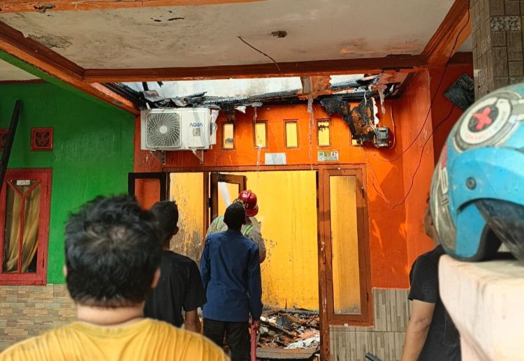 Petugas dari Dinas Pemadam Kebakaran & Penyelamatan Kabupaten Bekasi melakukan proses pendinginan di rumah yang terbakar.