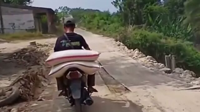 Salah seorang pengendara melintas di Jalan Raya CBL yang terletak di Kampung Sasak Bakar, Desa Kertamukti, Kecamatan Cibitung, Kabupaten Bekasi. Ruas jalan ini mengalami kerusakan parah sejak tahun lalu akibat tanah amblas. Agar memungkinkan dilalui kendaraan secara bersamaan dari dua arah, jalan tersebut ditutup sementara menggunakan plat besi.