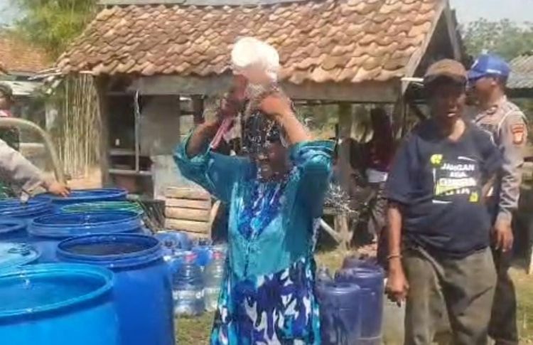 Seorang warga di Kampung Jereged, Desa Nagasari, Kecamatan Serang Baru, spontan mandi menggunakan air bersih dari mobil tangki saat bantuan air dari Polsek Serang Baru tiba, Senin (13/07).